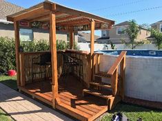 a wooden gazebo sitting on top of a lush green field next to a swimming pool