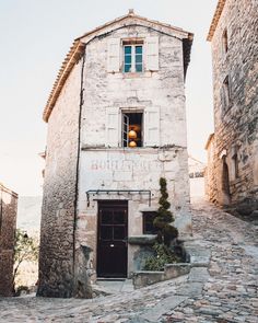 an old stone building with a bell on the door and steps leading up to it