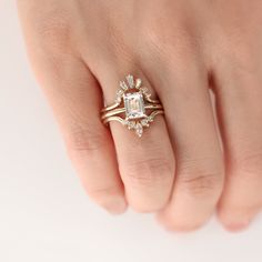 a woman's hand with a gold ring and an engagement ring on her finger