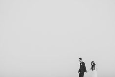 a bride and groom standing on the beach in black and white with their arms around each other