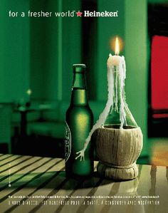 a beer bottle sitting on top of a table next to a lit candle in a vase