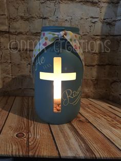 a lit candle with the words he is risen and a cross on it in front of a brick wall