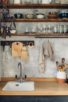 a kitchen counter with dishes and utensils hanging on the wall above it, next to a sink