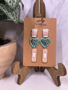 a pair of earrings is on display next to a potted plant