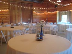 tables and chairs are set up in a large room with lights strung from the ceiling