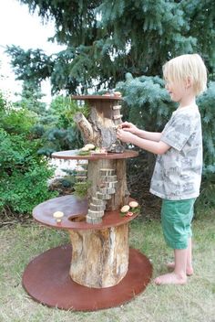 a little boy standing next to a tree stump with a bird house on top of it