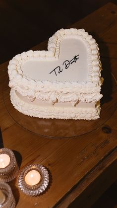 a heart shaped cake sitting on top of a wooden table next to two lit candles