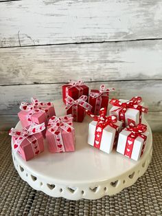 small red and white gift boxes with bows on a cake platter for valentine's day