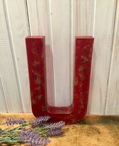 the letter u is made out of red wood and has lavenders in front of it