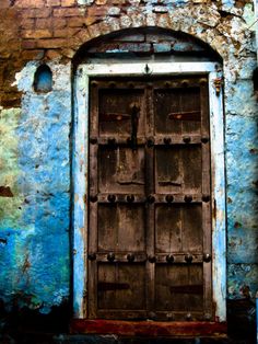 an old wooden door in front of a blue wall