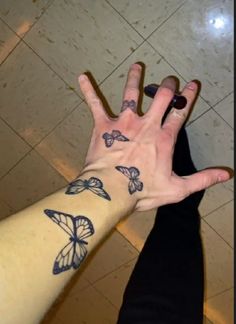 a person's hand with butterfly tattoos on it