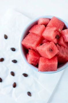 a bowl filled with watermelon slices on top of a white napkin next to coffee beans