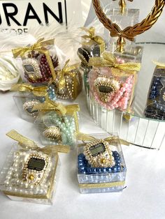 four small clear boxes filled with different colored candies and pearls on top of a white table