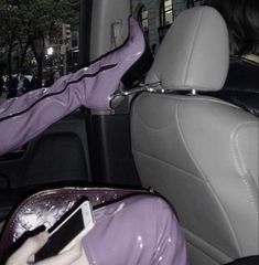 a woman sitting in the back seat of a car holding a cell phone