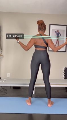 a woman is standing on a yoga mat with her arms outstretched and the words lat pulldown above her head