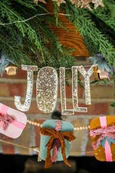 the word joy is hanging from a garland with presents on it and decorations around it