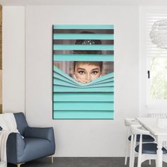 a woman's face peeking out from behind the blinds in a room with blue chairs