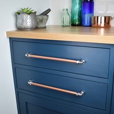 a blue dresser with copper handles in a kitchen