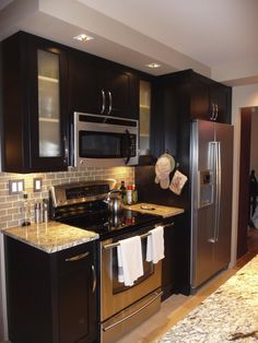 a kitchen with black cabinets and stainless steel appliances