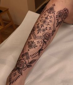 a woman's leg with flowers and leaves on the bottom half of her arm