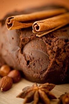 a loaf of chocolate cake with cinnamon and star anise next to it on a wooden surface