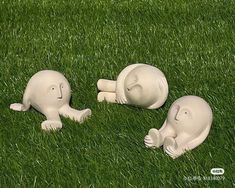 three small white ceramic animals laying in the grass