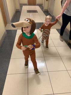 two children in costumes walking down a hallway