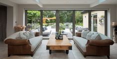 a living room filled with furniture and a wooden table in front of a glass door