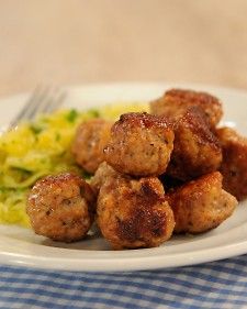 meatballs and spaghetti on a white plate with a blue checkered table cloth next to it