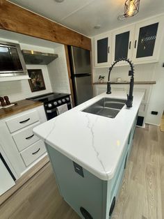 a kitchen with white cabinets and an island in the middle is seen from across the room