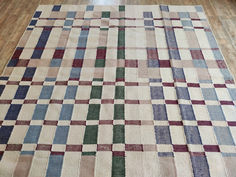 a multicolored checkered rug on the floor in a room with hard wood floors