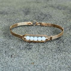 A contemporary little bracelet consisting of five strands of 14kt gold filled wire with a center design featuring five 4mm smooth glowing opalite beads and accented with two smaller 14kt gold filled beads. This sweet bracelet is stylish and simple, and it's stackable with most of my other wirewrapped bracelet styles! The opalite shifts from white to blue to lavender overtones, depending on what you wear it with, making it the perfect accessory for every outfit! The sturdy built-in hook and eye c Adjustable 14k Gold Filled Wire Wrapped Bracelets, Bead Bangles, Gold Bangle Bracelet, Beaded Bracelet, Wire Bracelet, Gold Wire, Gold Bangles, 14kt Gold, Bracelet Gift