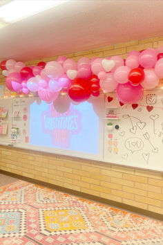 balloons are hanging from the ceiling in front of a projector screen with writing on it