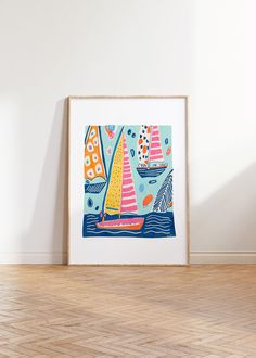 an art print with sailboats floating in the ocean on a wood floor next to a white wall