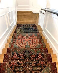 a set of stairs with rugs on the bottom, and a cat sitting on top