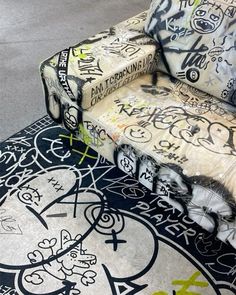 a couch covered in graffiti sitting on top of a floor next to a rug with writing all over it