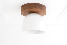 a white light hanging from the ceiling in a room with wood trimming on it