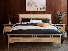 a bed with wooden headboard and foot board in a room that has wood paneling on the walls