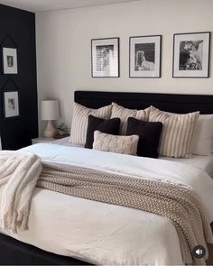 a bed with white sheets and black pillows in a bedroom next to pictures on the wall