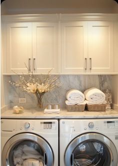 a washer and dryer in a white laundry room with marble counter tops on the wall