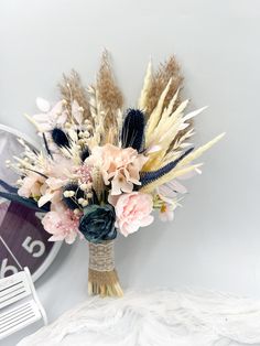 a vase filled with lots of flowers on top of a white table next to a clock