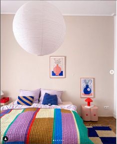 a bed room with a neatly made bed and a large white ball hanging from the ceiling