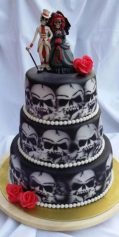 a wedding cake decorated with skulls and roses