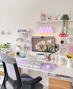 a desk with a computer, keyboard and flowers on the top shelf in front of it