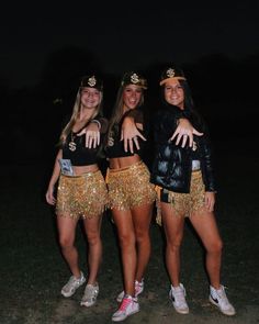 three young women dressed in gold sequins posing for the camera