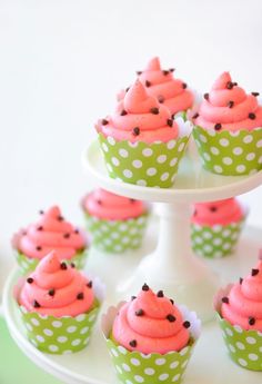 cupcakes with pink frosting and sprinkles on a cake stand