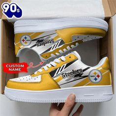 a pair of yellow and white sneakers with the pittsburgh football team on them in a cardboard box