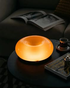 a table that has a light on top of it next to a book and coffee cup