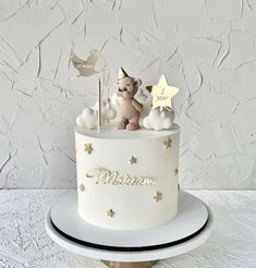 a white cake with gold stars and a teddy bear on top