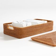 a wicker basket with folded towels and napkins in it on a white surface